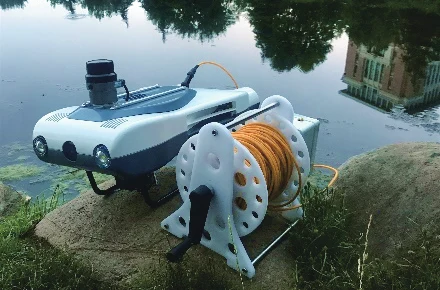 White Pengpai Ocean PX-MiniROV with a cable reel beside water, from the manufacturer's PX-MiniROV brochure section.