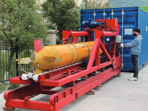 Pengpai Ocean manufacturer catalogue photograph showing a yellow and orange AUV on red launch/recovery rails beside a blue container; pictured vehicle and PX-900 compatibility unconfirmed.